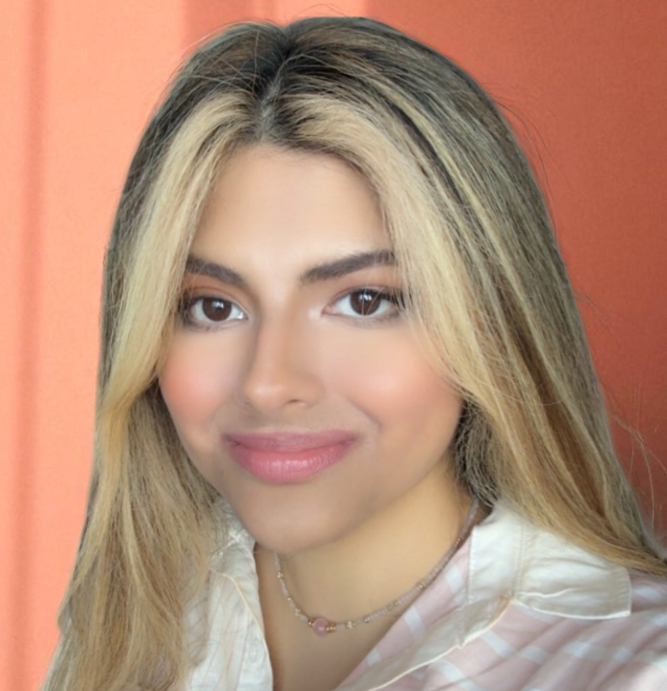 A young woman with light olive skin and blonde highlights smiling at the camera